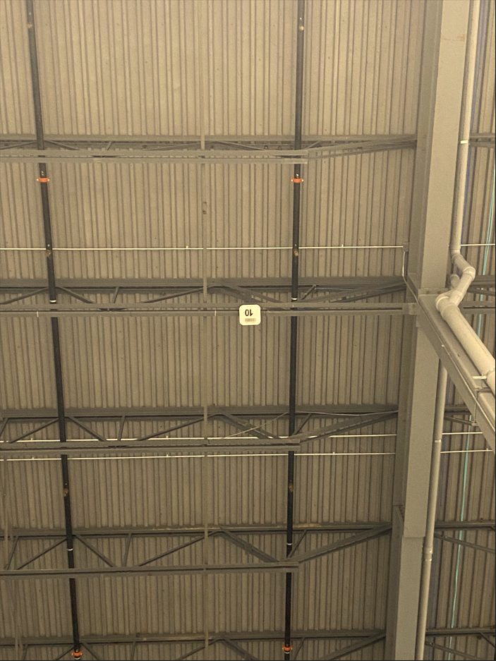 A wireless access point mounted on a high open steel warehouse ceiling